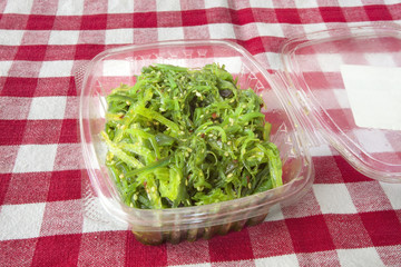 Seaweed salad on red and white checkered tablecloth. Horizontal.