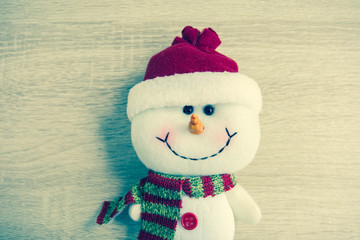 Snowman laying On wooden table, with vintage filter.