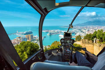Helicopter cockpit flies in port of Malaga from the Gibralfaro Castle, Andalusia, Spain, with pilot...