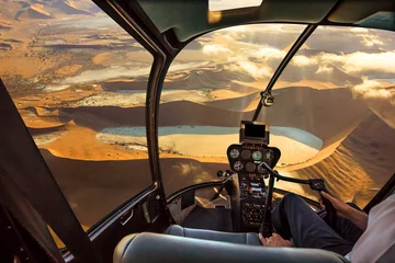 Tuinposter Helicopter cockpit flies in Deadvlei, Sossusvlei desert in Namib Naukluft National Park, Namibia, with pilot arm and control board inside the cabin. © bennymarty