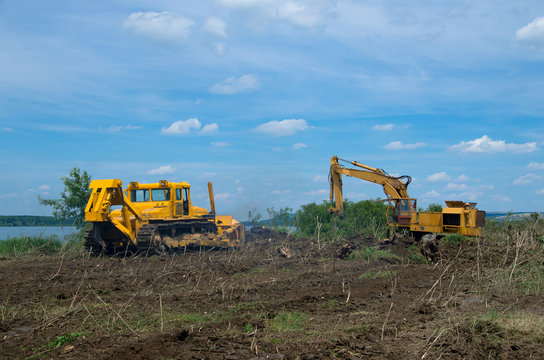 Excavator and bulldozer clearing forest land.