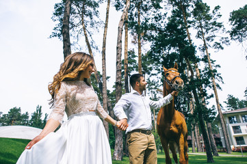 A newlywed couple standing next to a horse