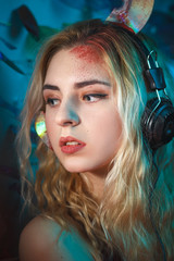 Fototapeta premium Concept: deadly music, sound kills. Beautiful young woman in headphones with bloody parts of cd sticking out of her head. Accident/murder victim. Undead.