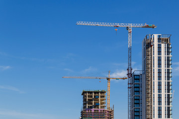 Building crane and construction site under blue sky.
