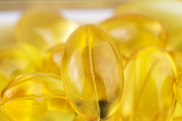 Natural food supplement, yellow gel pills Vitamin E capsules, macro image.