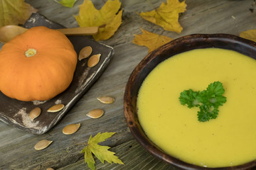 Winter Pumpkin and Carrot Cream Soup with parsley in hand made c