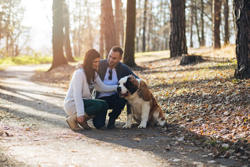 Naklejka na ściany i meble People and dogs. Young couple enjoying nature outdoors together with their Saint Bernard puppy