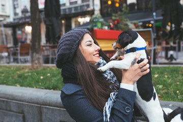 Fototapeta premium Beautiful young brunette woman enjoying city street outdoor together with her gorgeous Jack Russell terrier.