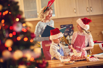 smiling mother and children baking cookies at home .