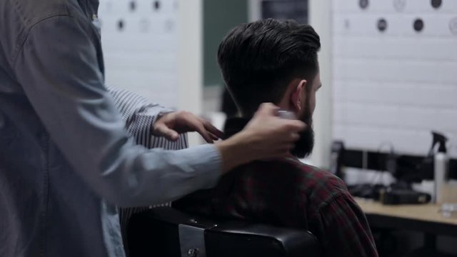 Barber taking off salon cape from client with beard and using a talc