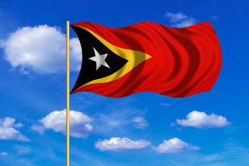 Flag of East Timor waving on blue sky background