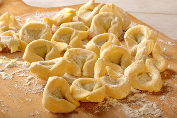 Freshly prepared italian tortellini on wooden background