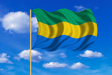 Flag of Gabon waving on blue sky background