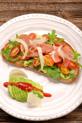 Avocado sandwich on fresh bread with arugula ham tomato and chee
