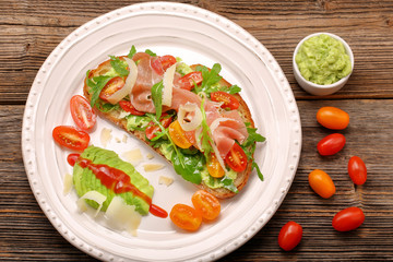 Avocado sandwich on fresh bread with arugula ham tomato and chee