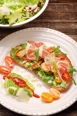 Avocado sandwich on fresh bread with arugula ham tomato and chee