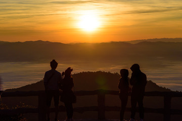 Fototapeta na wymiar silhouette style of two couple on the top of view point in the mountain while watching sunrise and sea of fog or mist