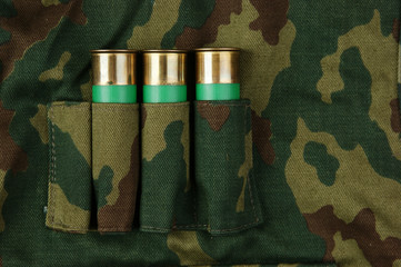 Old hunting cartridges and bandoleer on camouflage background