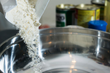 close up of pouring the flour in to the stainleass blow preparation step to cooking some food that by flour