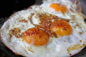 Fried eggs in with red hot chilly peppers