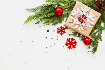 Christmas and New Year background with thuja branch, decorations and present wrapped in craft paper with snowflakes. Flat lay, top view. Place for text.