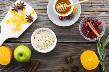 Rolled oats, honey, apples, pomegranates, persimmons for the winter season breakfast, pastries and other dishes. Top view. The concept of seasonal food.