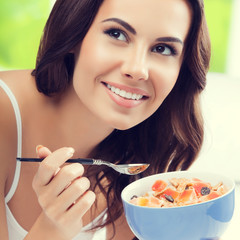 Cheerful beautiful young woman eating muslin