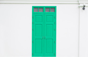 traditional green door wooden of an old on white wall,in Thailand
