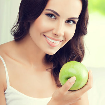 Young happy smiling woman with green apple, indoors