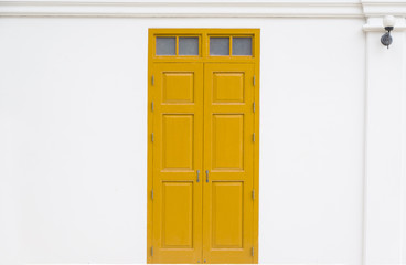 traditional yellow door wooden of an old on white wall,in Thailand