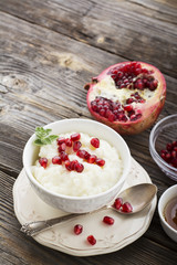 Fragrant warm homemade rice milk porridge with sugar and pomegranate seeds on a wooden background. The concept of healthy, seasonal dishes