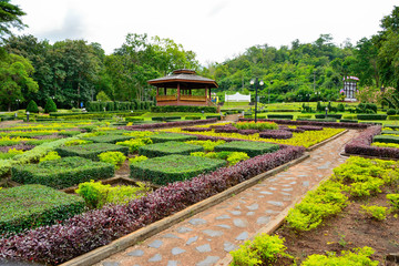 Fototapeta premium Country cottage garden path. Thai style pavilion is located in the middle with tree background.