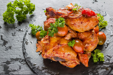 Chakhokhbili, chicken stew, cooked with tomatoes, bell peppers, spices and herbs. Black stone background.