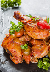 Chakhokhbili, chicken stew, cooked with tomatoes, bell peppers, spices and herbs. Black stone background.