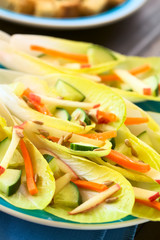 Fresh salad of endive leaves, cucumber, carrot, apple and sunflower seeds, photographed with natural light (Selective Focus, Focus one third into the salad)