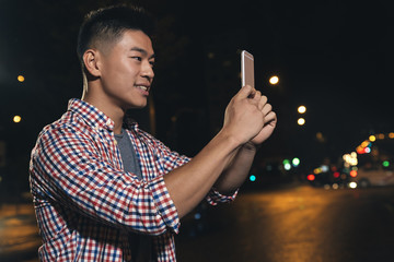 Young asian man with headphones taking a picture.