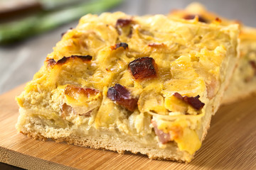 Traditional German Zwiebelkuchen savory onion cake with bacon, photographed with natural light (Selective Focus, Focus on the big bacon piece in the middle of the image)