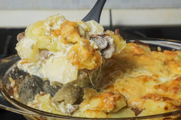 Homemade scalloped potatoes with mushrooms and cheese. Focus on spoon