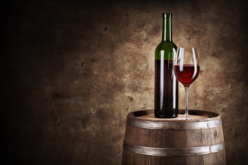 Bottle and glass of red wine on wooden barrel
