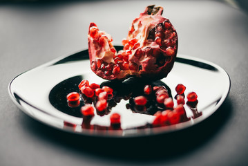 pomegranate and pomegranate seeds on a black plate