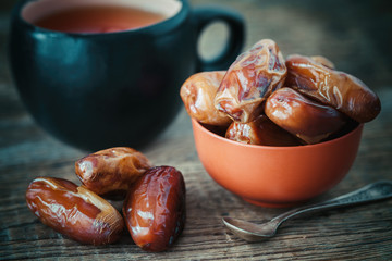Dates fruits in bowl and tea cup on background. Retro toned.