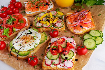 Variety of vegetarian toast sandwiches with salmon, raddish, tomatoes, cucumber, avocado,fried egg and sweet pepper
