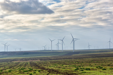Fototapeta na wymiar Eolian field and wind turbines farm on a cloudy day