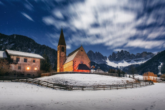 Winter night view on Santa Maddalena church. The movement of the clouds. Val di Funes. Dolomites. Italy.