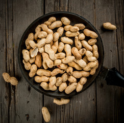 Freshly roasted peanuts in a frying pan, in the shell, top view