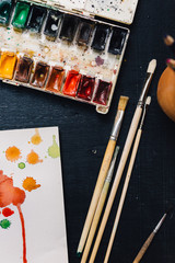 Crop from above view of watercolor palette and paintbrushes.