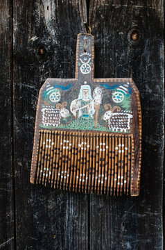 Old ukrainian traditional painted wooden wool comb hanging on dark timber background