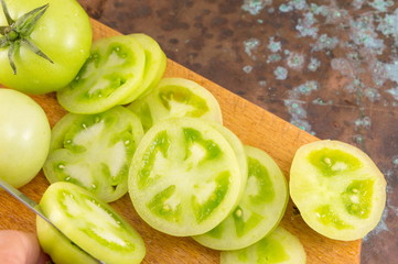 slicing green tomatoes on a cutting board