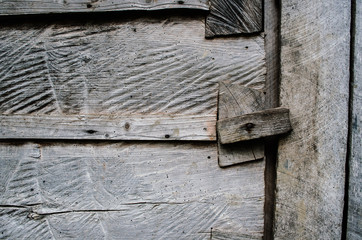 Dark gray weathered rustic rural wooden barn wall, door, gate, primirive lock timber planks closeup texture background. Empty sapce for text, lettering, copy.