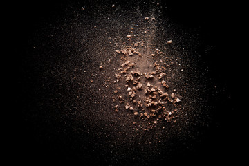 pink broken and spilled eye shadow on a black isolated background